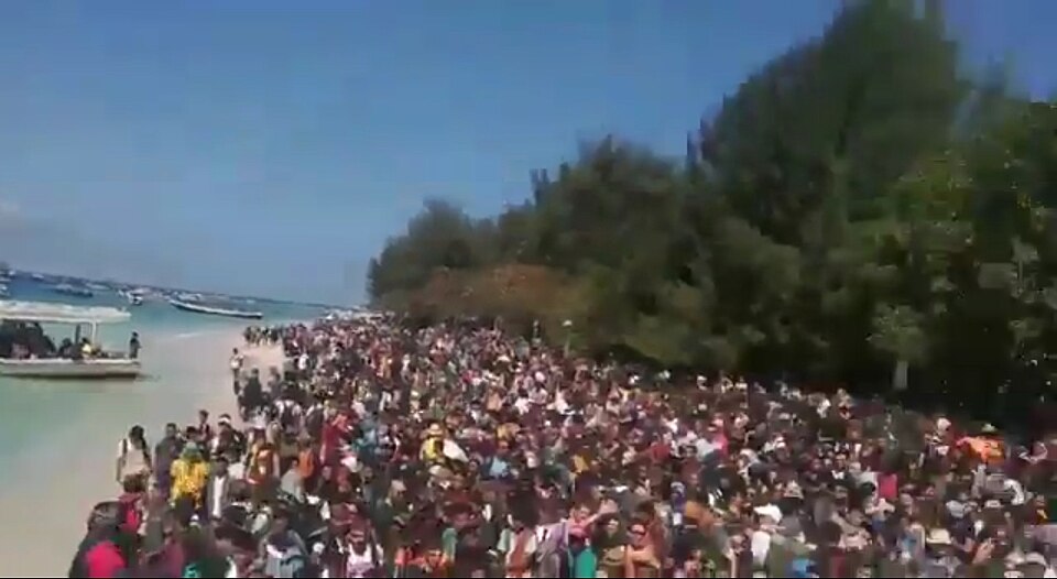 Tourists on the beach of Gili Trawangan, near Lombok, crowding up to embark on evacuation boats
