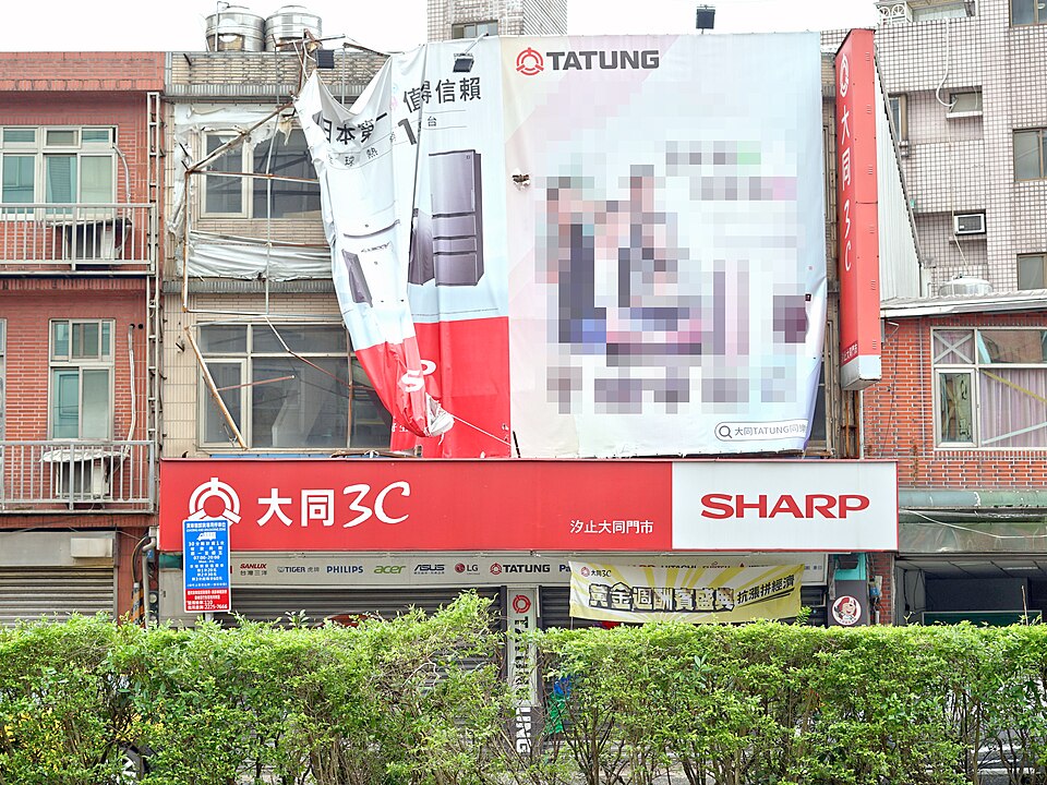 ​從新北市汐止區大同路二段人行道遠望大同3C展售中心汐止大同門市，外牆廣告帆布左半邊被康芮颱風吹毀。拍攝時未營業。